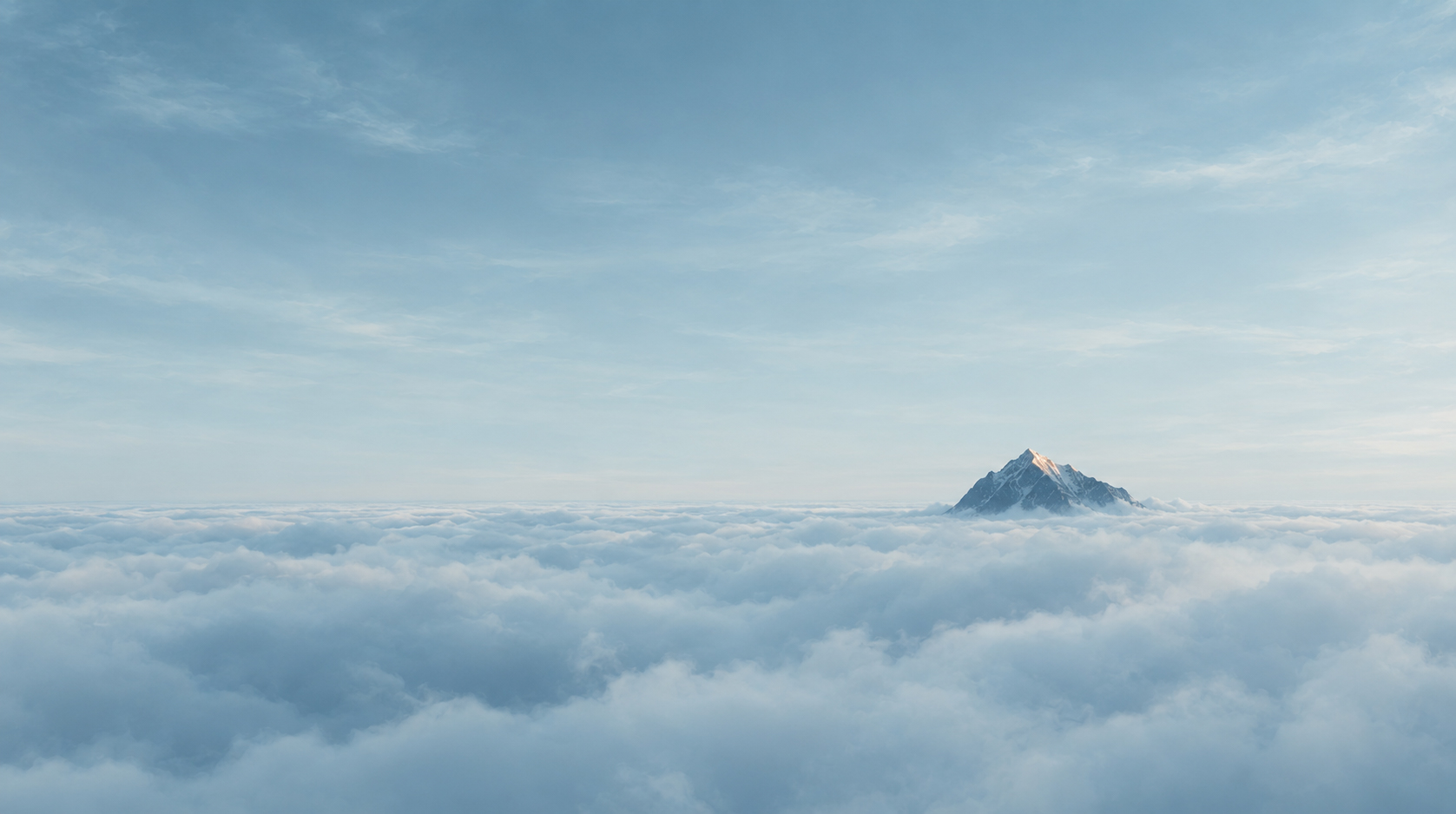 A single mountain summit breaking through a sea of cloud, its tip catching the first light.